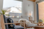 Relax in this luxurious living room, featuring stunning mountain views from a large window.