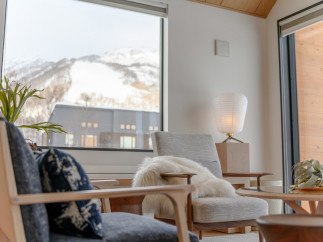 Relax in this luxurious living room, featuring stunning mountain views from a large window.