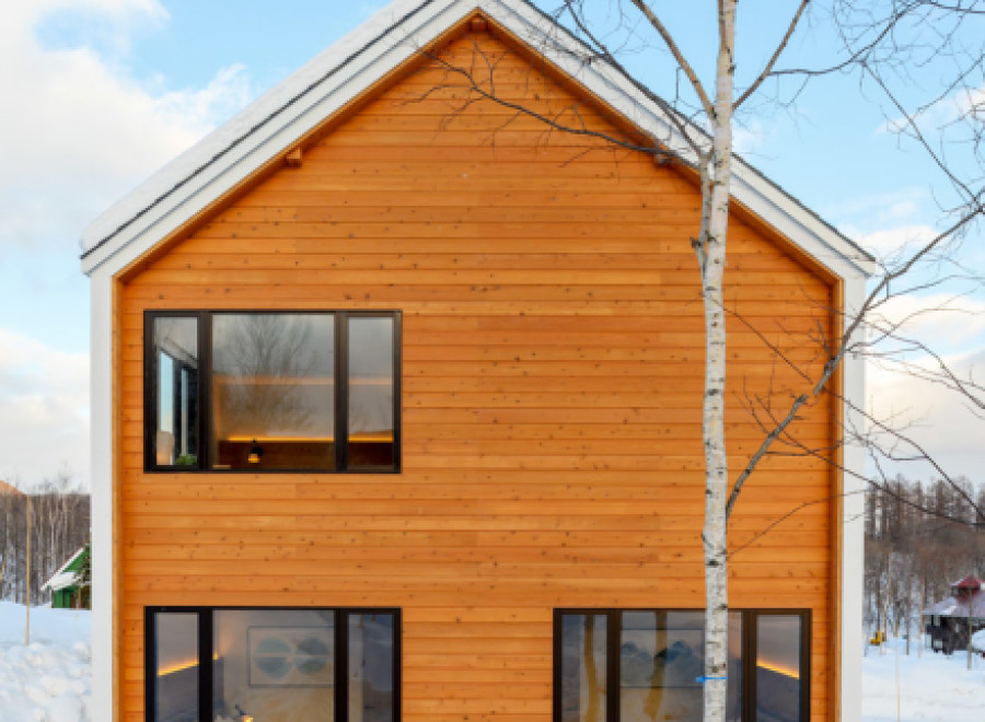 This stunning A-frame cabin boasts a modern design with expansive windows offering breathtaking views of the snowy landscape.