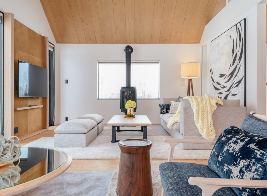 This stunning living room boasts a vaulted wood ceiling, large windows offering abundant natural light, and a cozy fireplace as a focal point.