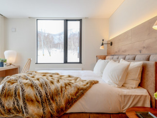 This luxurious bedroom boasts a king-size bed with plush bedding and a cozy faux fur throw, perfect for relaxing after a day on the slopes.