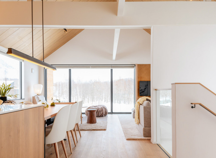 This stunning property boasts an open-concept living area with floor-to-ceiling windows offering breathtaking views of a snow-covered landscape.
