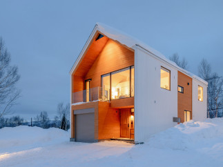 This stunning modern home boasts a unique design with a blend of white and wood siding, creating a cozy yet contemporary feel.