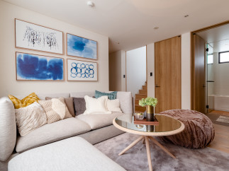 This stunning living room boasts a light and airy feel, complemented by a cozy sectional sofa and plush pouf.