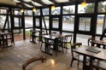 This sunroom restaurant boasts a rustic-chic design with dark wood tables and chairs, complemented by soft, warm lighting.