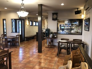This cozy restaurant boasts a warm, inviting atmosphere with terracotta tile floors and dark wood furniture.