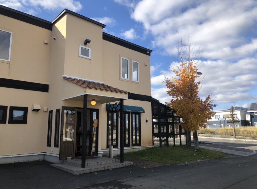 This charming, light beige commercial building features a unique architectural design with dark brown accents and a terracotta-tiled roof.