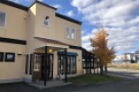 This charming, light beige commercial building features a unique architectural design with dark brown accents and a terracotta-tiled roof.