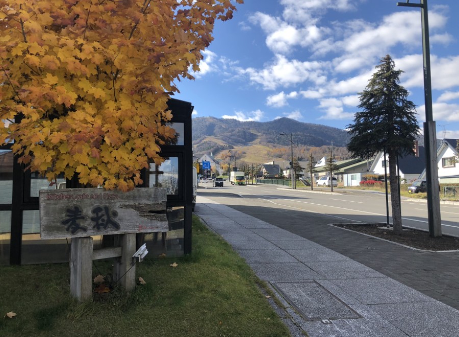 This charming roadside cafe boasts a rustic wooden sign, inviting passersby to enjoy its kitchen, cafe, and pizza offerings.
