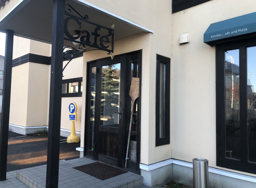 This charming cafe boasts a quaint exterior with a welcoming entrance, marked by a stylish "Cafe" sign and a convenient parking spot nearby.