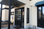 This charming cafe boasts a quaint exterior with a welcoming entrance, marked by a stylish "Cafe" sign and a convenient parking spot nearby.
