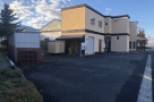 This commercial property features a two-story building with ample parking, a separate storage shed, and a spacious lot.