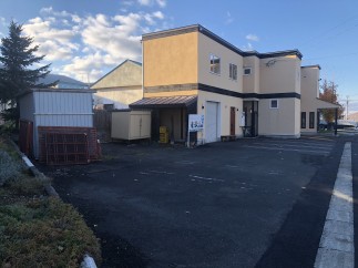 This commercial property features a two-story building with ample parking, a separate storage shed, and a spacious lot.