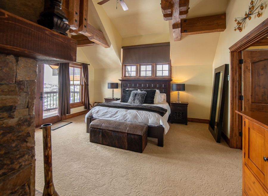 Luxurious mountaintop bedroom with stunning views, featuring a king-size bed, plush carpet, and a cozy fireplace.