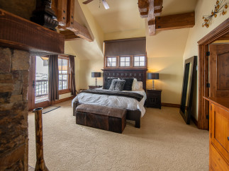 Luxurious mountaintop bedroom with stunning views, featuring a king-size bed, plush carpet, and a cozy fireplace.