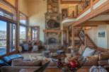 This stunning mountain home boasts a spacious open-plan living area with floor-to-ceiling windows offering breathtaking views.