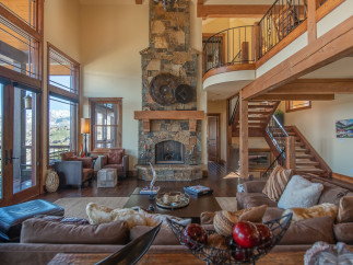 This stunning mountain home boasts a spacious open-plan living area with floor-to-ceiling windows offering breathtaking views.
