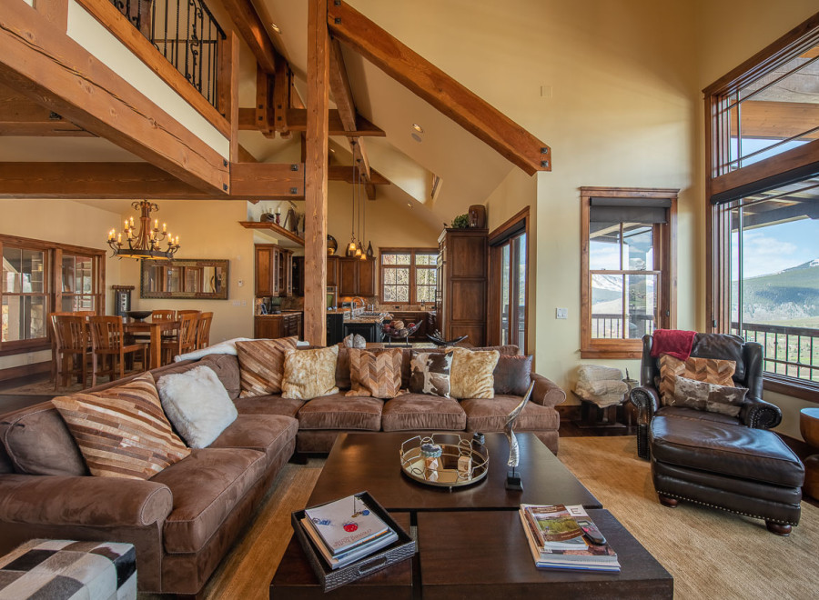 This stunning mountain home boasts an open floor plan with soaring ceilings and exposed beams, creating a warm and inviting atmosphere.
