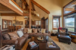 This stunning mountain home boasts an open floor plan with soaring ceilings and exposed beams, creating a warm and inviting atmosphere.