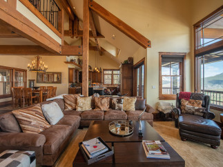 This stunning mountain home boasts an open floor plan with soaring ceilings and exposed beams, creating a warm and inviting atmosphere.