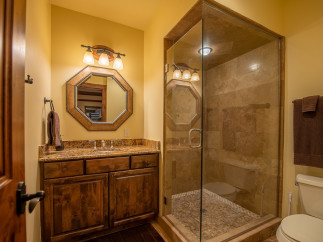 This luxurious bathroom boasts a spacious walk-in shower with glass enclosure and elegant stone tile.