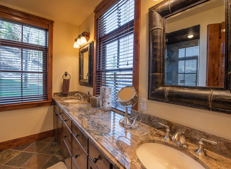 This luxurious bathroom boasts dual vanities with granite countertops and large mirrors, creating an elegant and spacious feel.