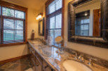 This luxurious bathroom boasts dual vanities with granite countertops and large mirrors, creating an elegant and spacious feel.