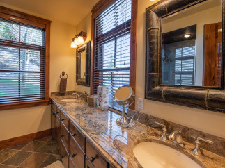 This luxurious bathroom boasts dual vanities with granite countertops and large mirrors, creating an elegant and spacious feel.