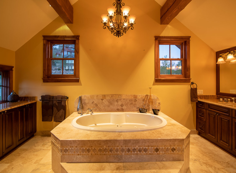 Luxurious master bathroom boasts a spacious soaking tub, complemented by elegant tilework and a stunning chandelier.