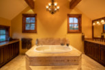 Luxurious master bathroom boasts a spacious soaking tub, complemented by elegant tilework and a stunning chandelier.