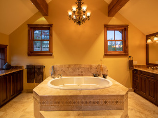 Luxurious master bathroom boasts a spacious soaking tub, complemented by elegant tilework and a stunning chandelier.