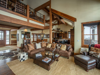 This stunning mountain home boasts a spacious open floor plan with soaring ceilings and exposed wooden beams.