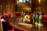 Elegant dining room featuring a rich, dark wood table surrounded by plush red velvet chairs.