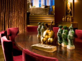 Elegant dining room featuring a rich, dark wood table surrounded by plush red velvet chairs.