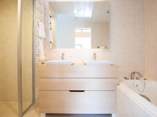 This luxurious bathroom boasts a double vanity with sleek sinks and ample storage, perfect for couples or families.
