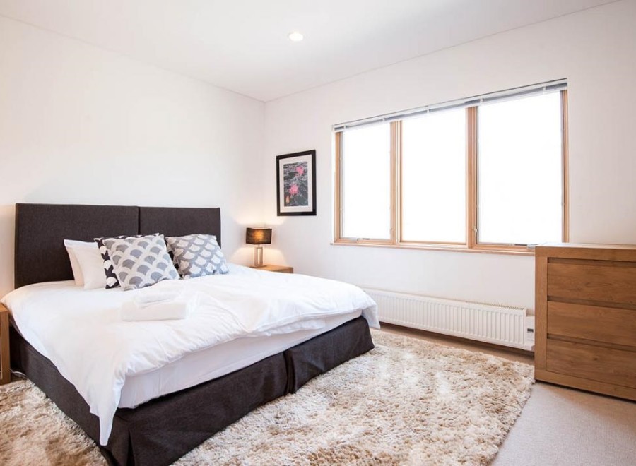 This bright and airy bedroom features a comfortable king-size bed with plush bedding, perfect for a relaxing stay.