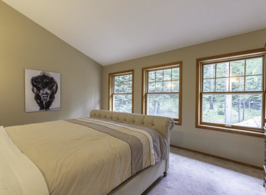 Discover a serene bedroom retreat with natural light streaming through three large windows.