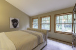 Discover a serene bedroom retreat with natural light streaming through three large windows.