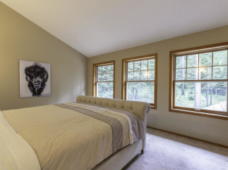 Discover a serene bedroom retreat with natural light streaming through three large windows.
