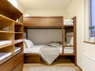 Cozy bunk bed room with built-in wooden shelves and drawers, perfect for storing luggage and personal items.