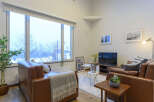 Cozy living room with large windows offering scenic views, leather sofas, and modern decor.