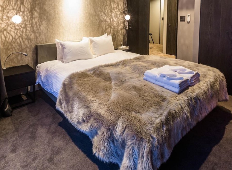 Luxurious bedroom with a cozy faux fur throw draped over the bed, plush bedding, and a modern nightstand.