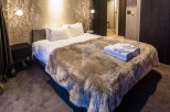 Luxurious bedroom with a cozy faux fur throw draped over the bed, plush bedding, and a modern nightstand.