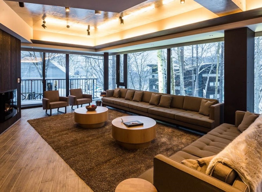 This luxurious living room boasts floor-to-ceiling windows showcasing breathtaking winter scenery, creating a serene and inviting atmosphere.