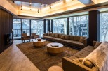 This luxurious living room boasts floor-to-ceiling windows showcasing breathtaking winter scenery, creating a serene and inviting atmosphere.