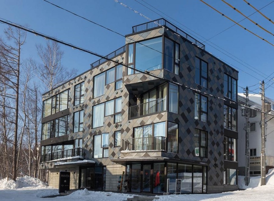 This modern building features a unique diamond-patterned facade, large windows offering ample natural light, and multiple balconies.