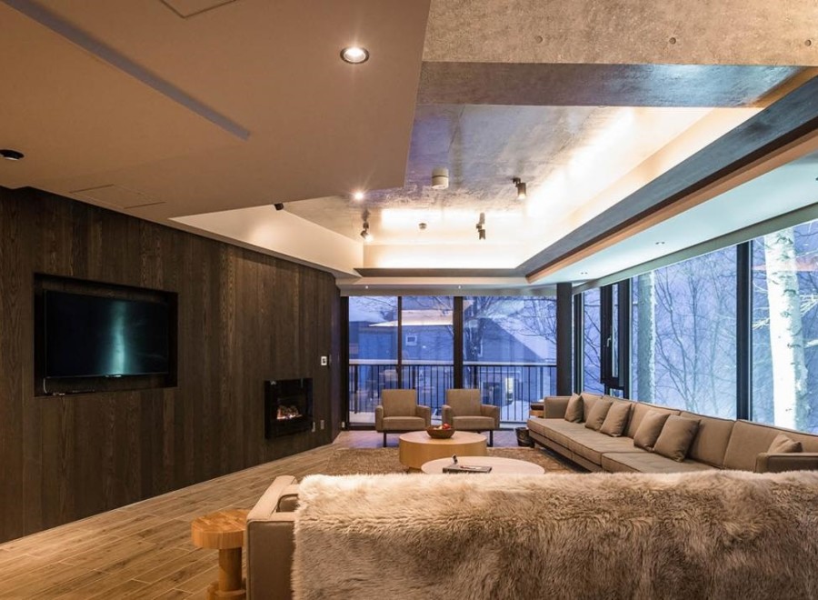 This luxurious living space boasts floor-to-ceiling windows showcasing breathtaking snowy landscapes, creating a serene atmosphere.