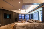 This luxurious living space boasts floor-to-ceiling windows showcasing breathtaking snowy landscapes, creating a serene atmosphere.
