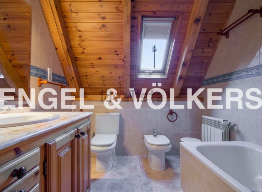 Charming attic bathroom with wooden beams, skylight, and modern fixtures.