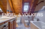 Charming attic bathroom with wooden beams, skylight, and modern fixtures.